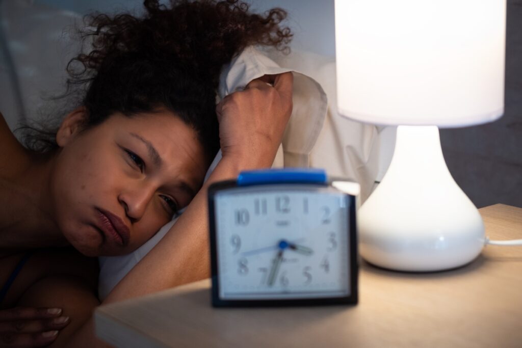 woman looking at the alarm clock with insomnia