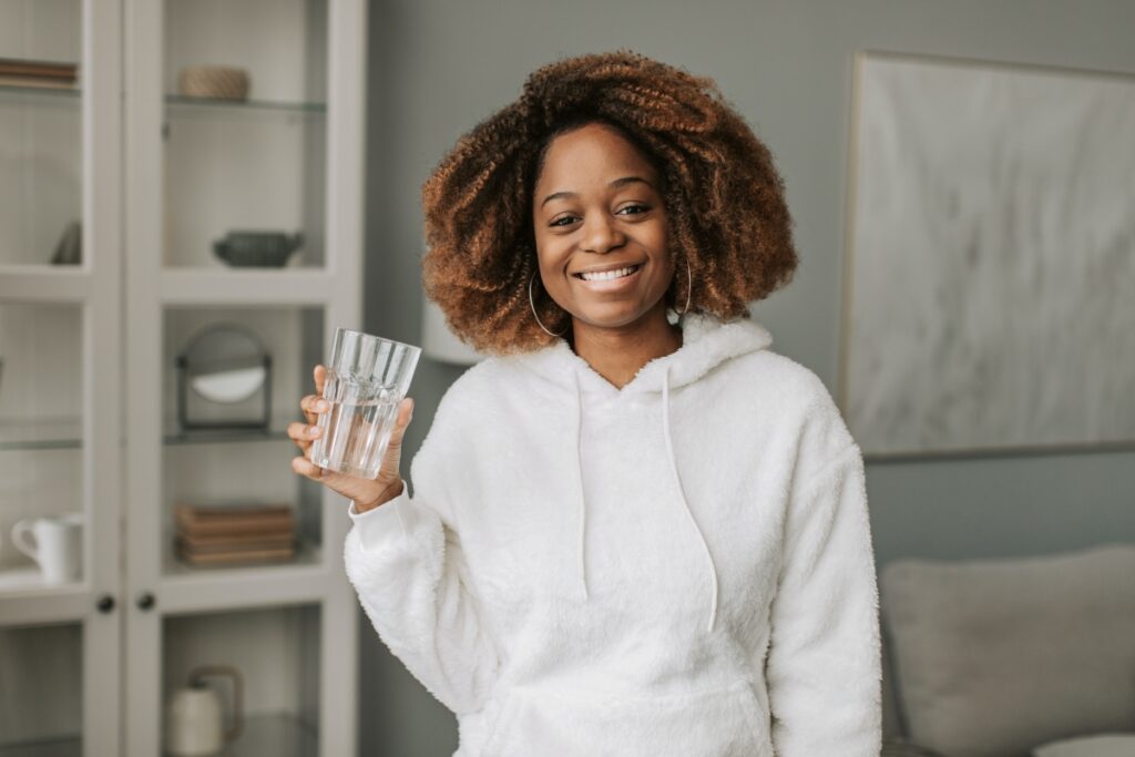 A woman with a glass of water smilling happy