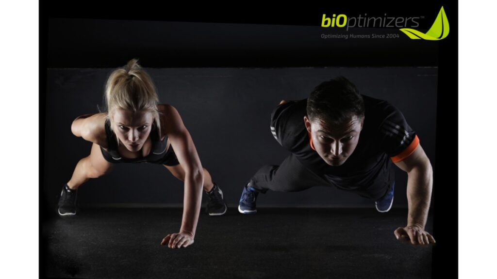 A man and a woman full concentrated doing a plank with one hand | Bioptimizers