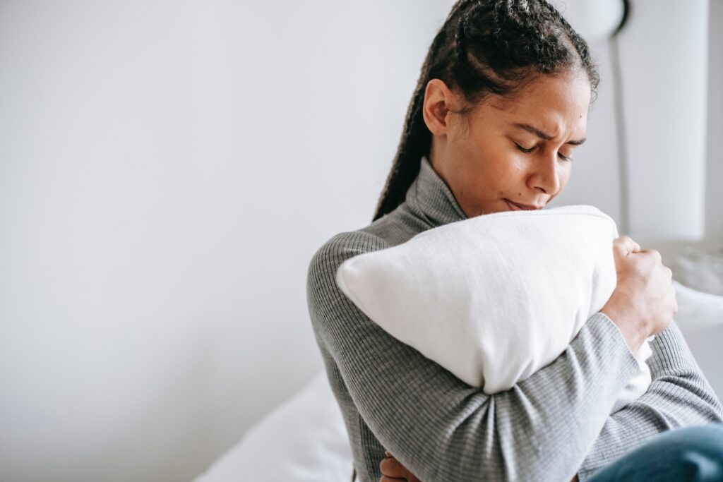 A woman in pain hugging a pillow