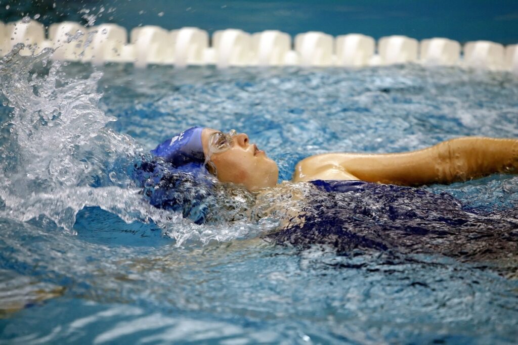 A sport woman in a pool backstroke swimming