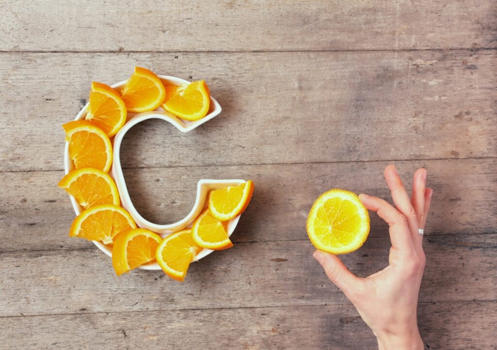 A C shape plate fill with orange slices and a hand holding the last part of the orange 