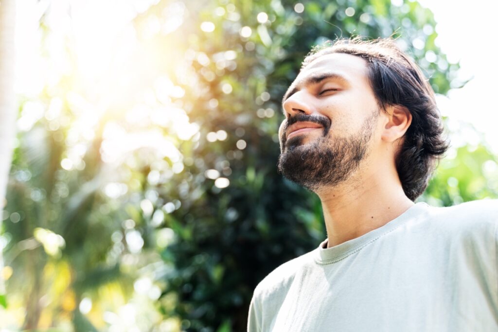 A young man feeling relieve and healthy, inhaling fresh air in the nature.