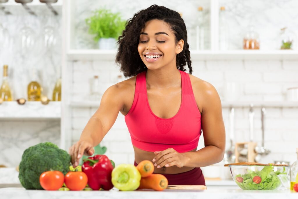 A sport woman in the kitchen choosing what vegtables to put in her salad