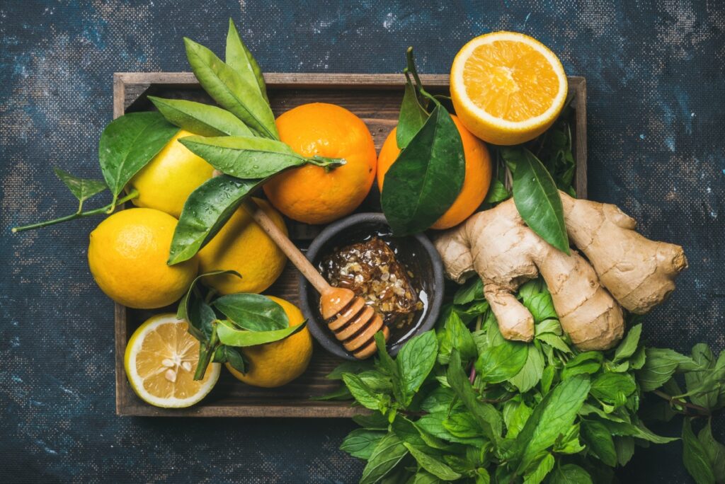 A cutting board fill with vitamin C rich foods like raw honey, orange, ginger and greens