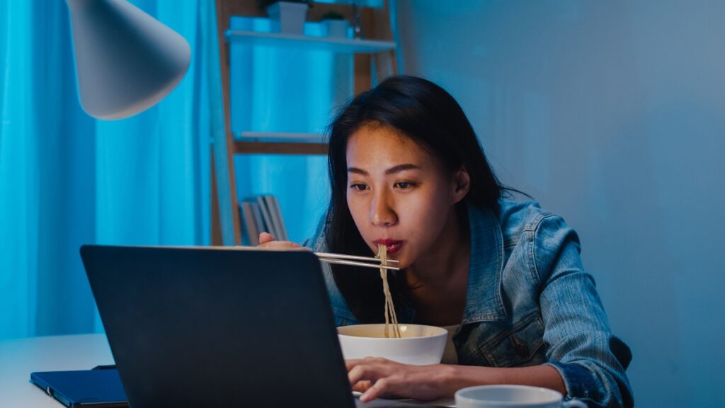 A young lady eating distracted with her laptop