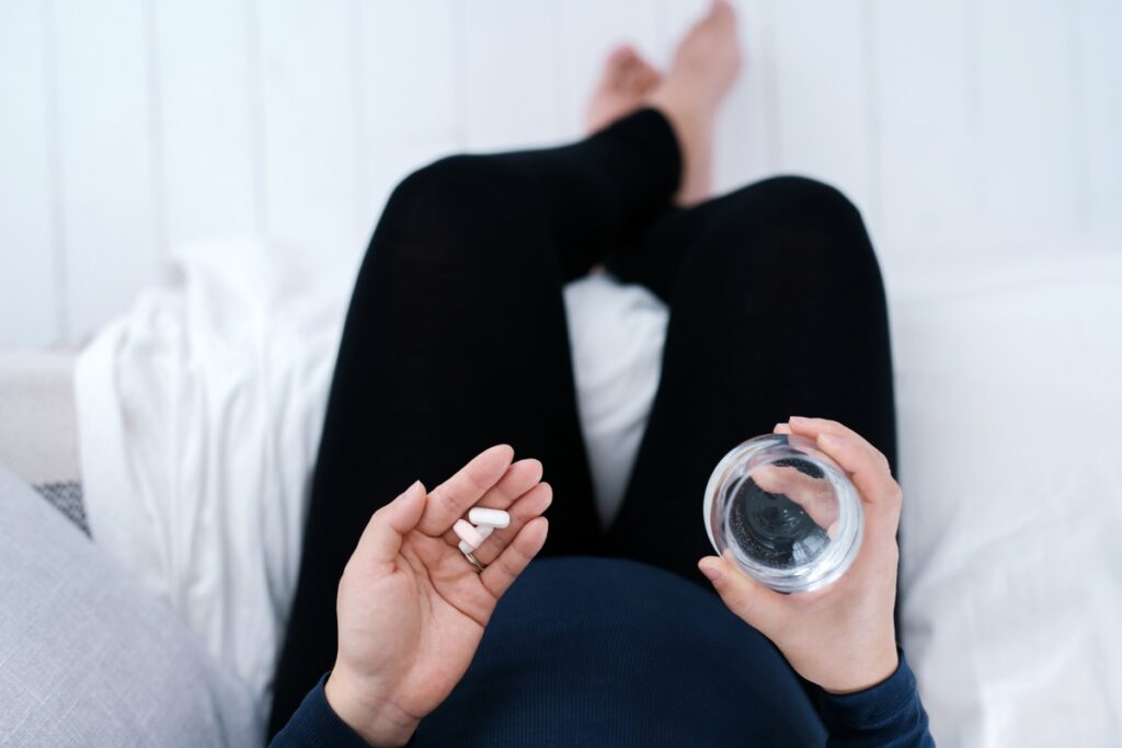 a woman holding HCL pills and a glass of water