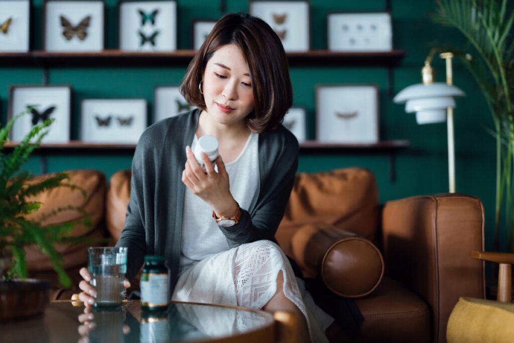 female patient reading the label of a bottle of supplement pills