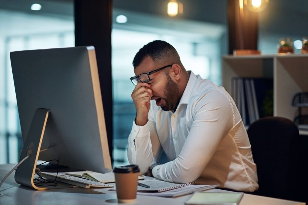 Shot of a young businessman experiencing stress during late night at work