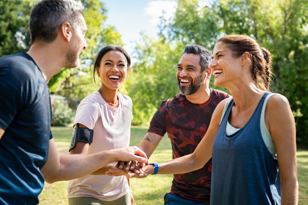 Laughing mature people putting hands together at park