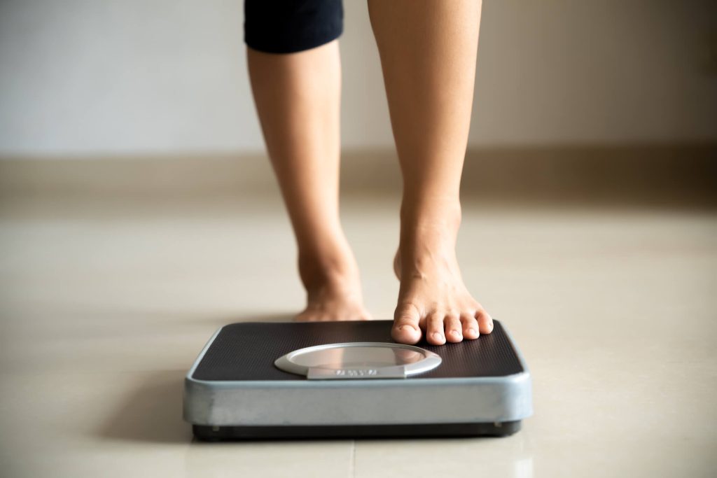 Female leg stepping on weigh scales