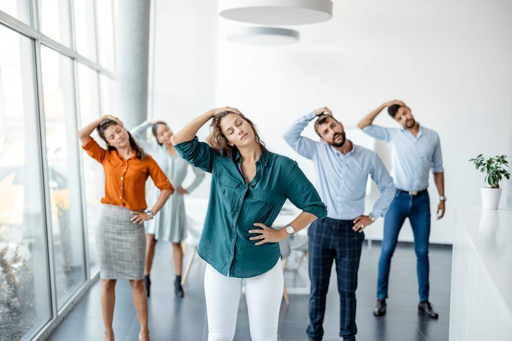 Diverse colleagues doing neck stretching exercise standing in office.