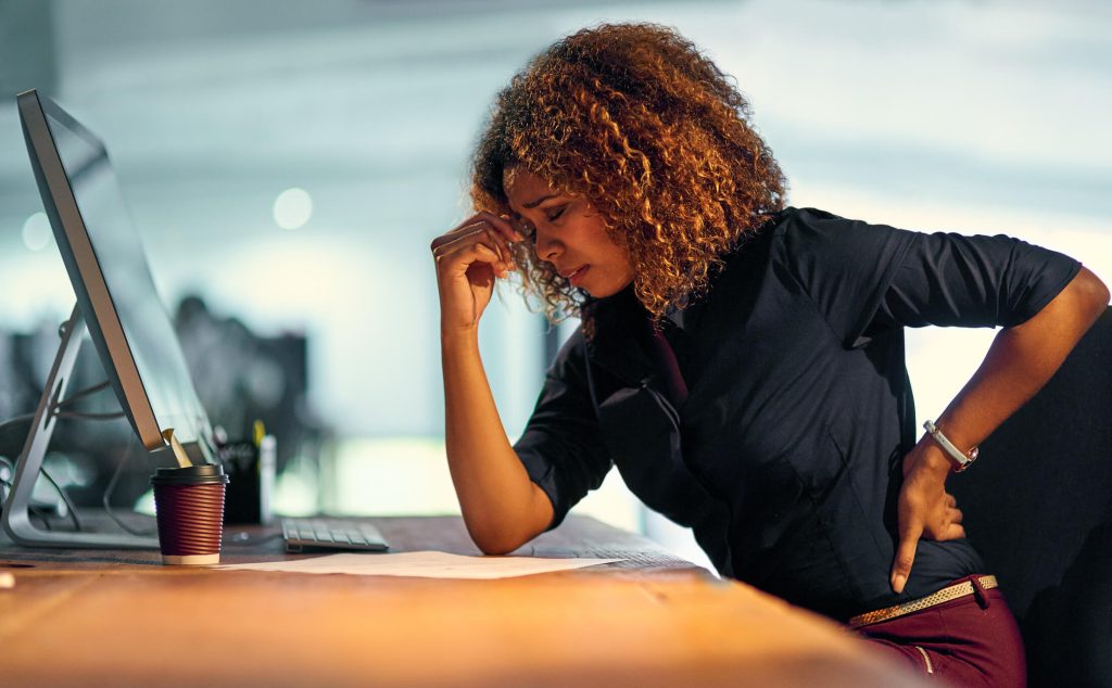 young businesswoman suffering from backache while working at night