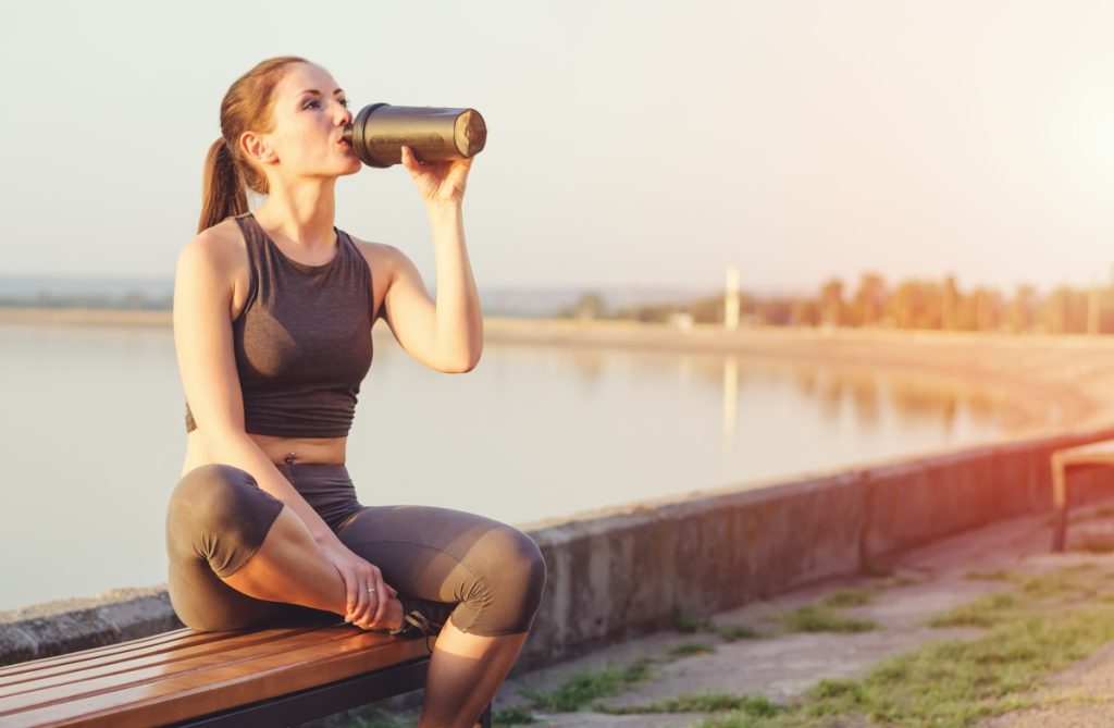  Sportswoman drinks protein from the shaker.