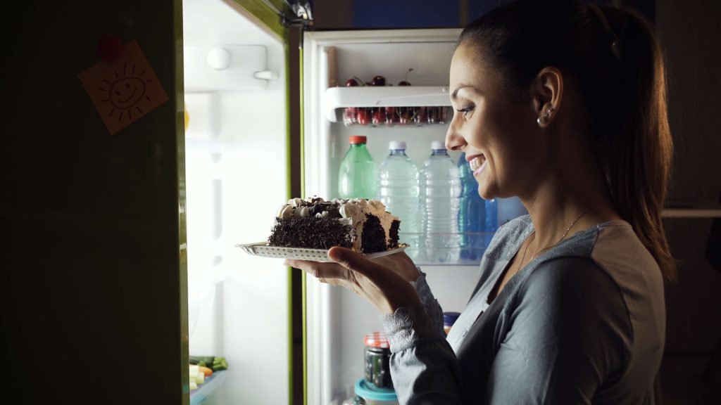 Greedy woman waking up at night and taking an unhealthy snack from the fridge.