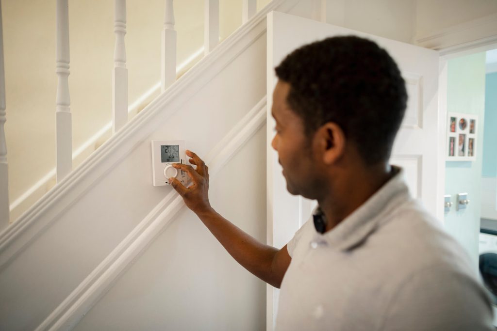  man turning down a thermostat in his home