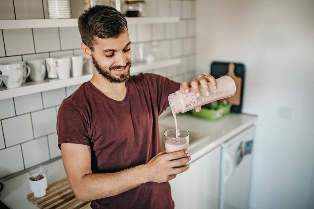 A man serving his protein shake out of the blender