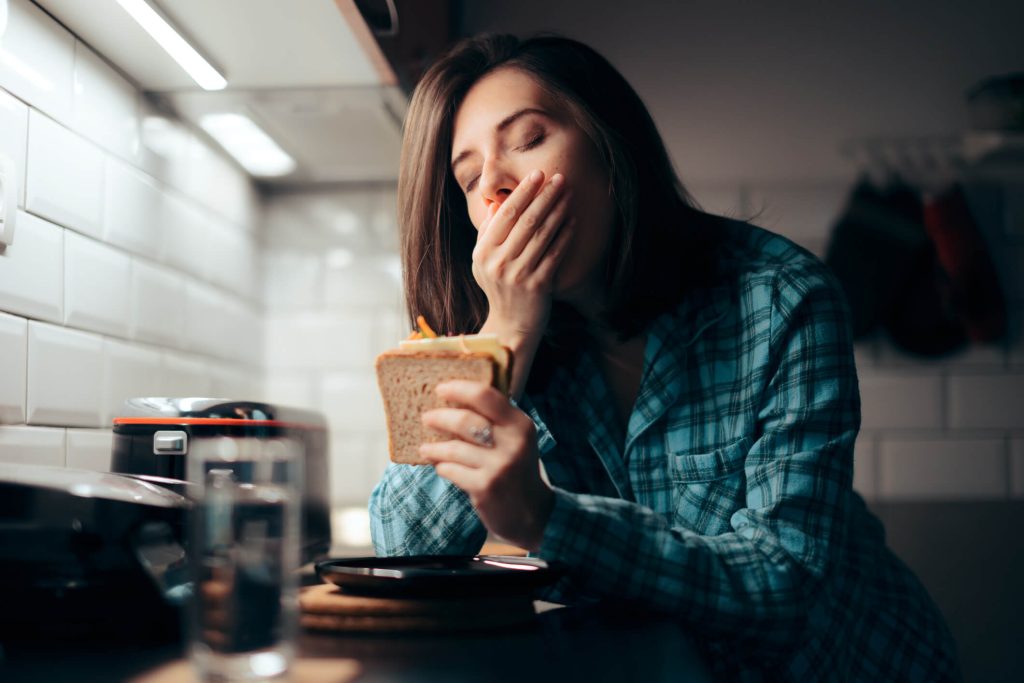 ired young person feeling hungry before going to sleep eating at night