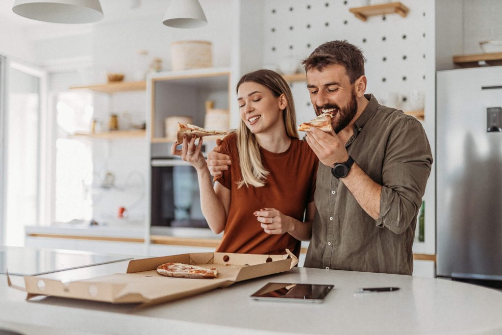 Couple eating pizza in the kitchen