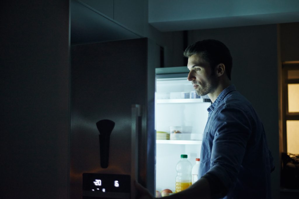shot of a man opening the fridge in the middle of the night 
