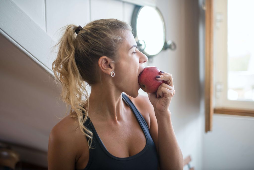 young lady coming back from the gym eating an apple