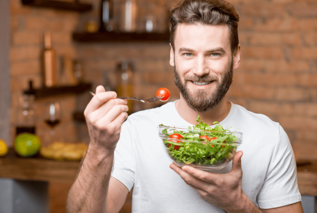 shot of a man eating a green salad