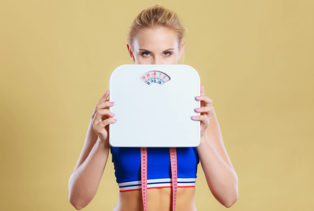 woman with a weighting scale and a measuring tape around her neck 