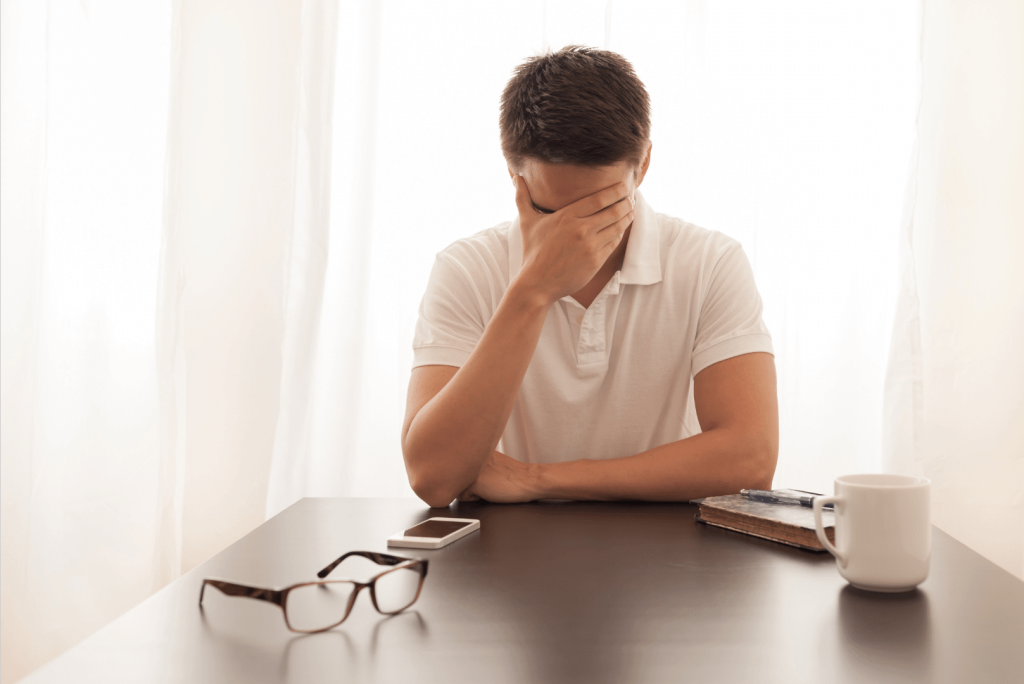 man sitting with hands over his head felling stresses