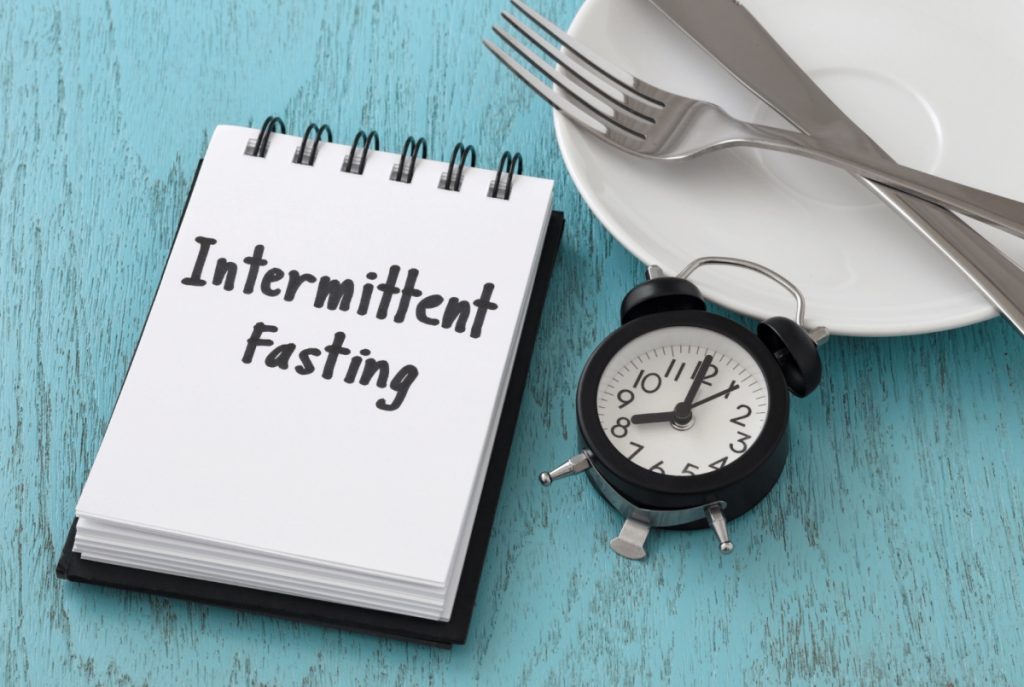 intermittent fasting. clock, silverware and plate over a table 