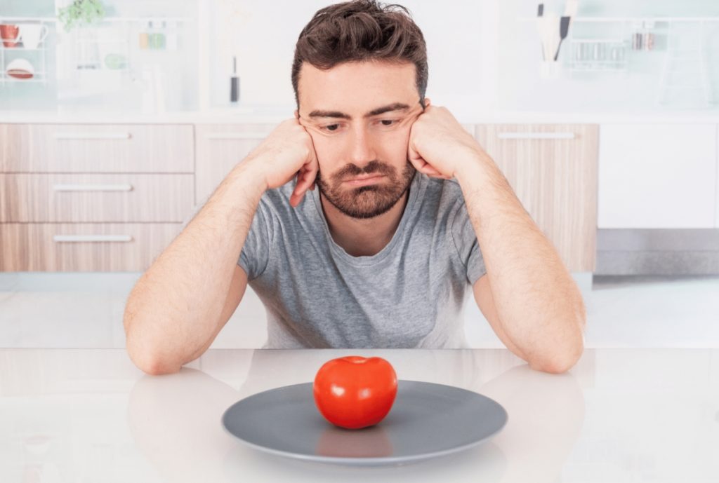 men looking at a tomato in a plate