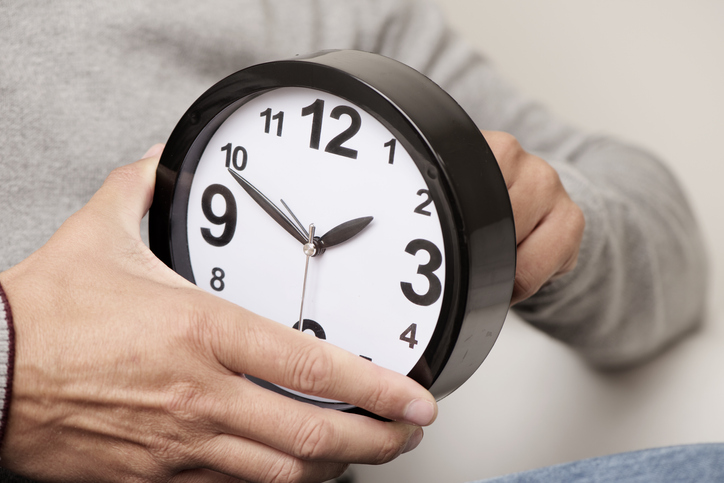 closeup of a young man adjusting the time of a clock