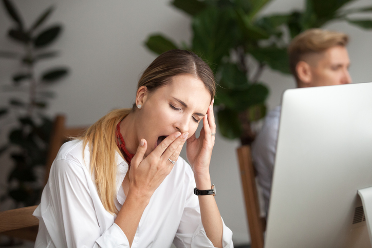 Bored businesswoman yawning at workplace feeling no motivation or lack of sleep tired of boring office routine.