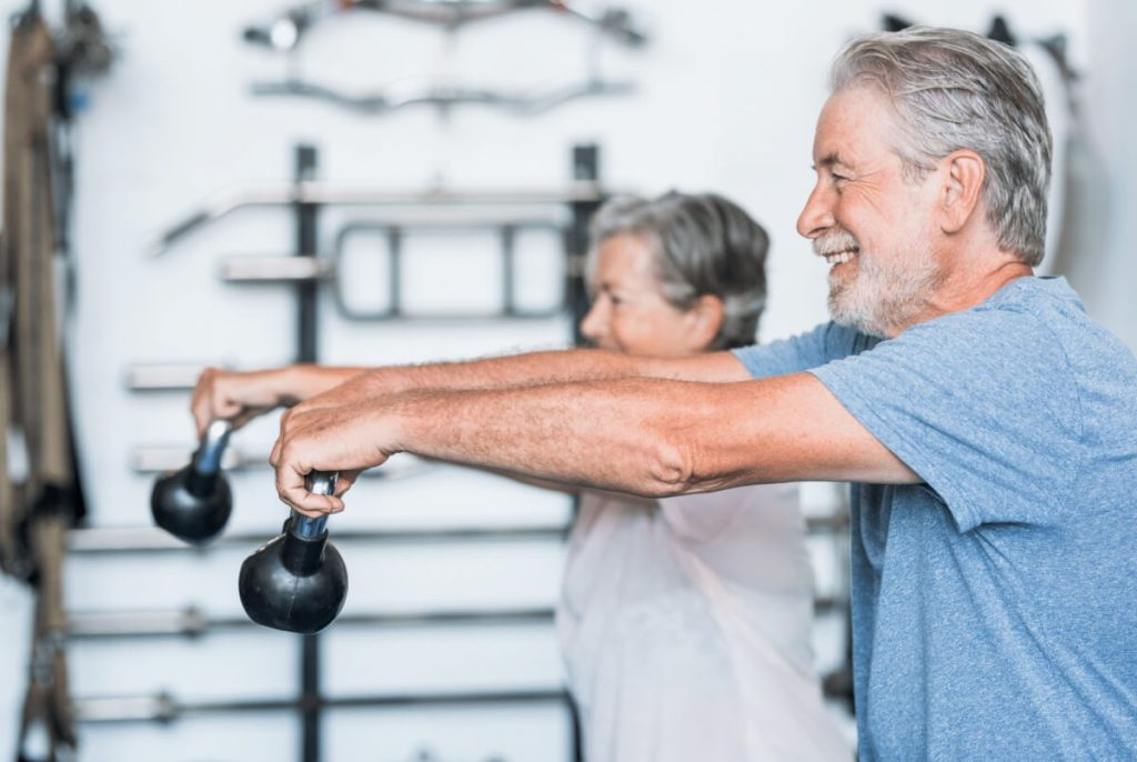 older couple doing squats with a russian ball 