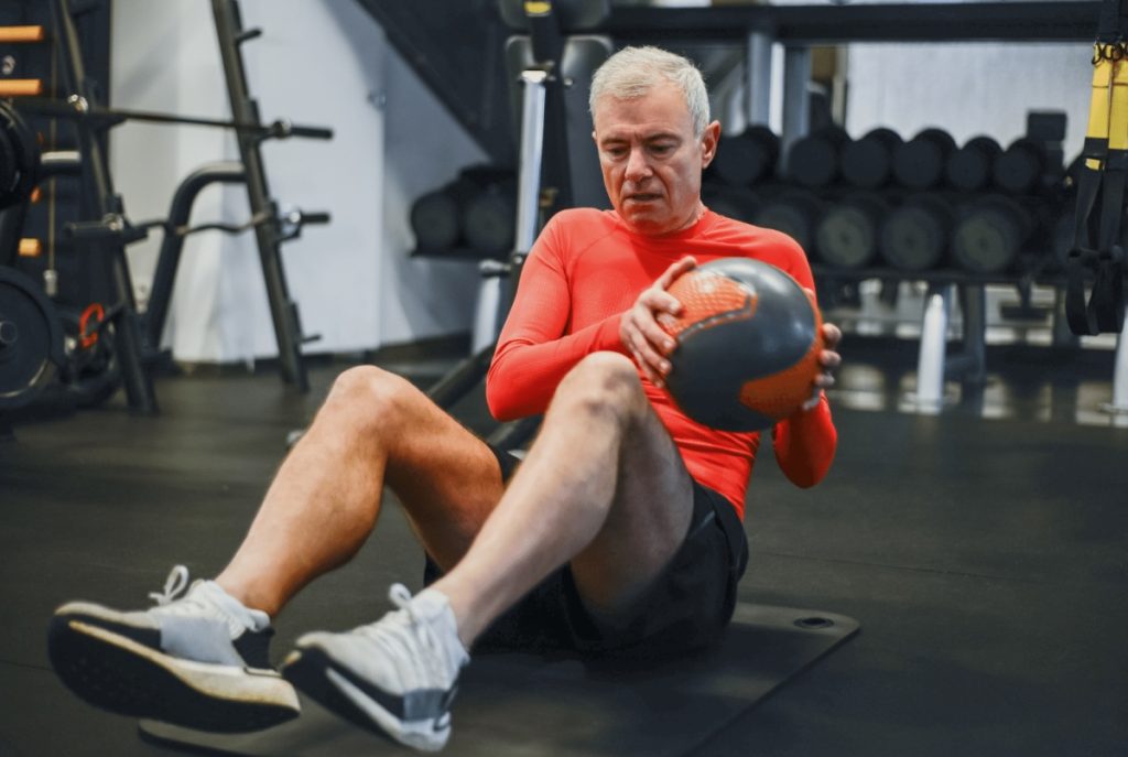 older man doing a med ball russian twist 