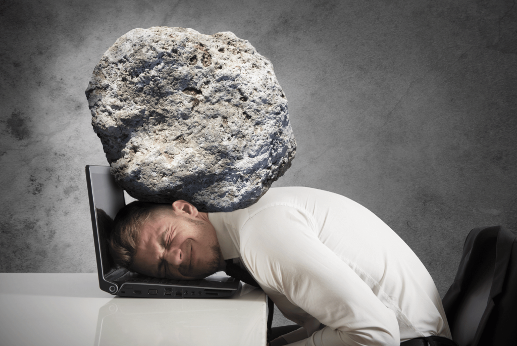 a rock over the head of a men lying over the laptop at work