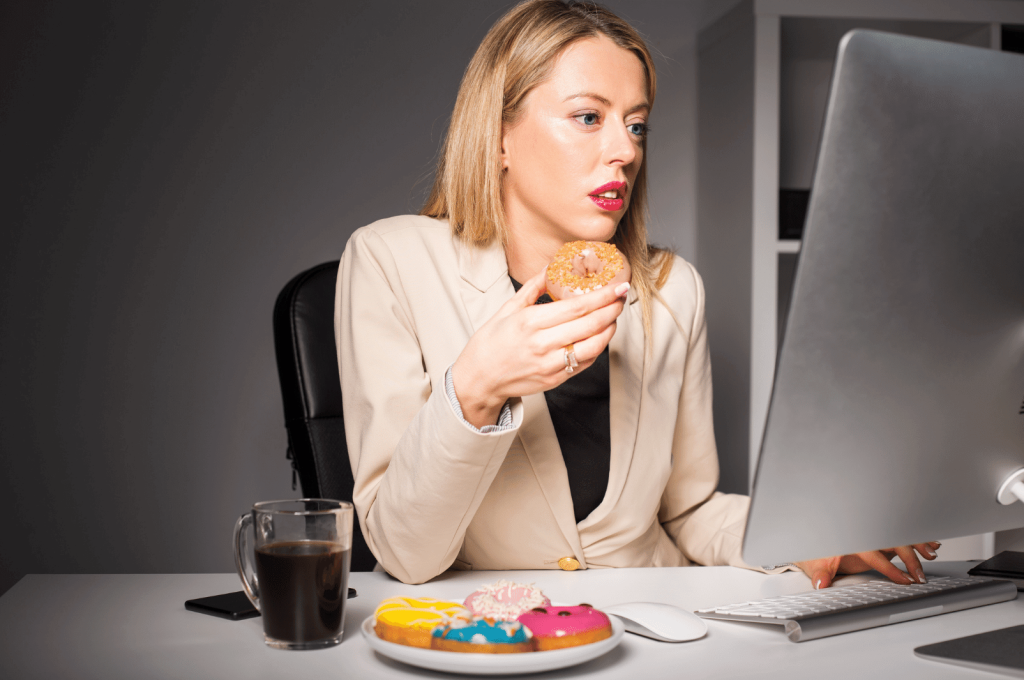 woman eating doughnut while working 