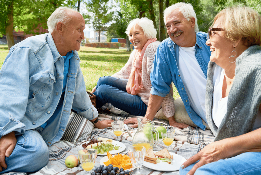 a group of elderly people having a picnic and smiling 