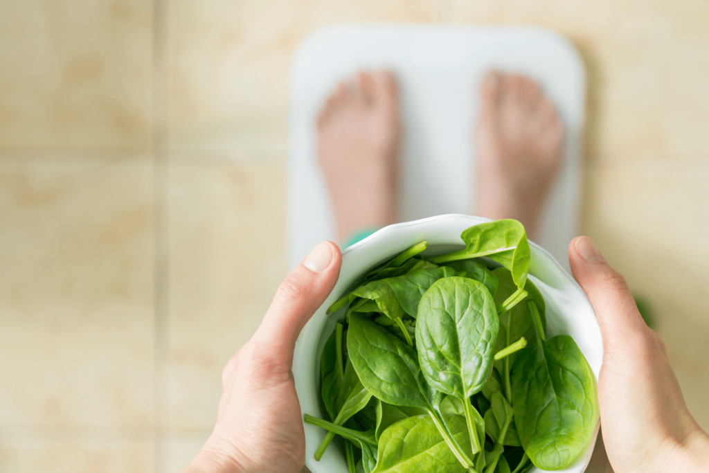 person holding a bowl of spinach