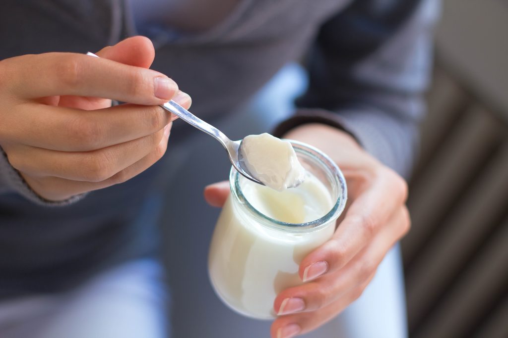 young beautiful woman eating yogurt at home