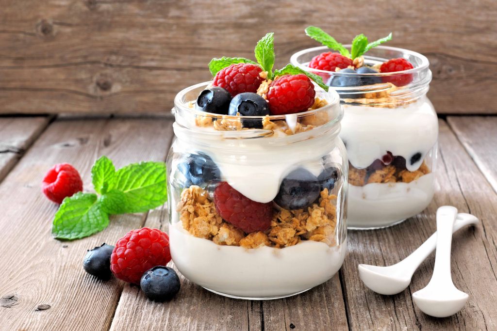 Blueberry and raspberry parfaits in mason jars, still life against a rustic wood background