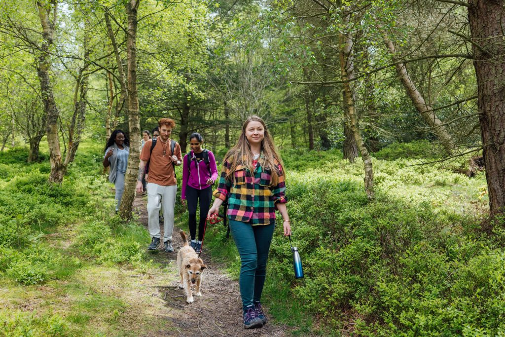 group of young people and a dog hiking 