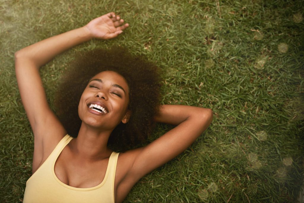 afroamerican woman lying down in the grass happy