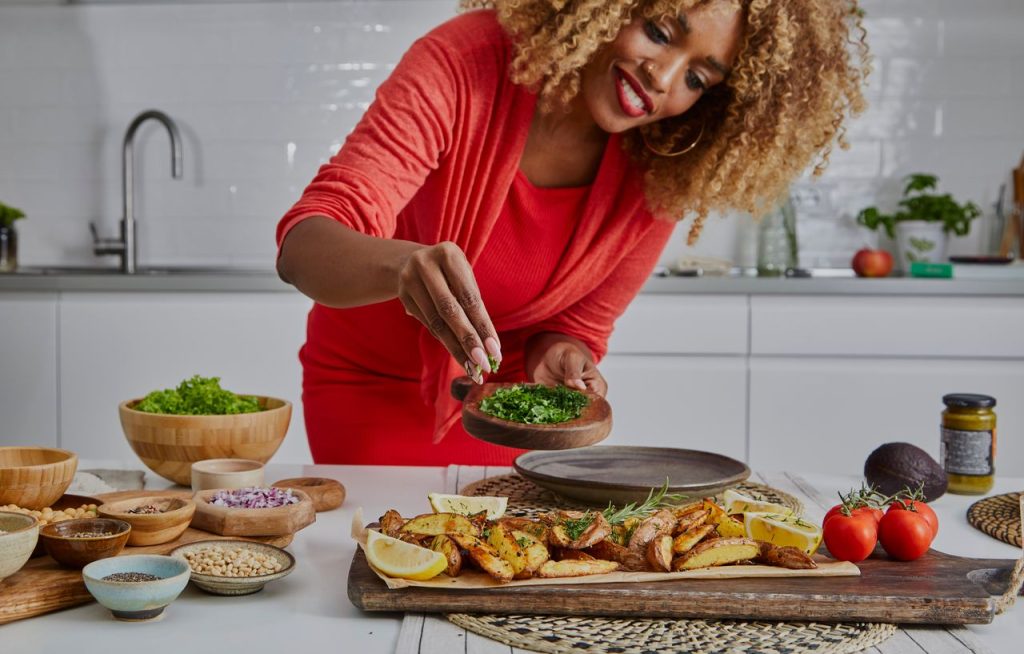 african american woman seasoning food at the kitchen