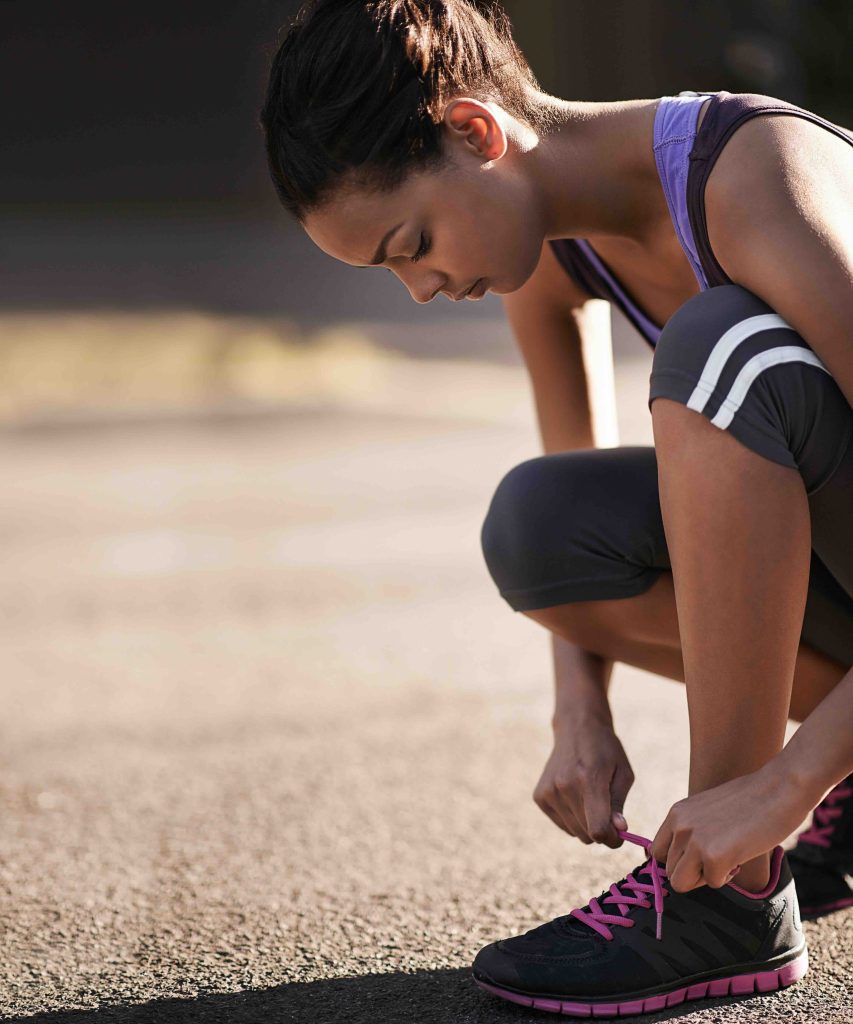 Shot of a runner tying her shoelaces before a run