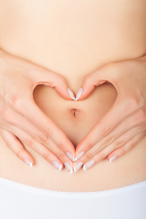 Closeup young woman in white underwear making heart shape with her hands on her belly