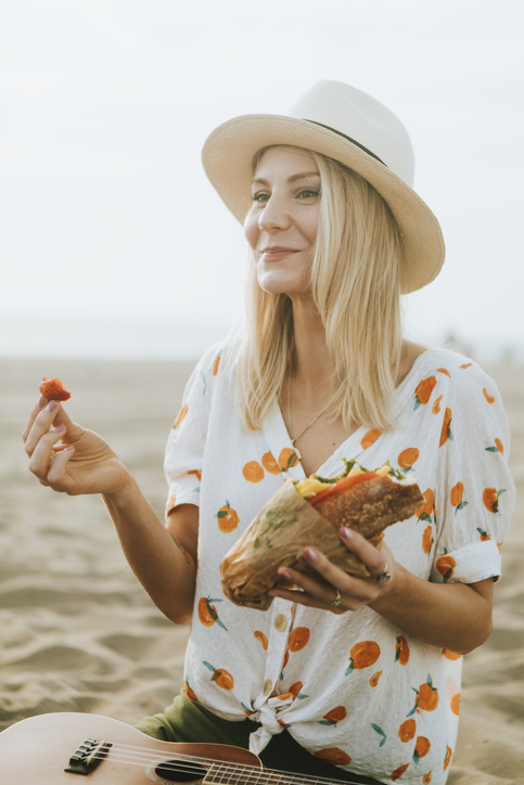 Woman eating a sandwich at a beach picnic