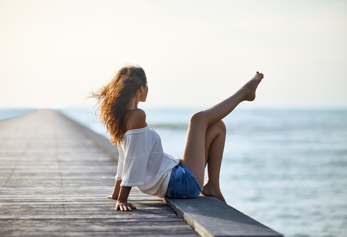 Beautiful woman relaxing on pier with sea view. 