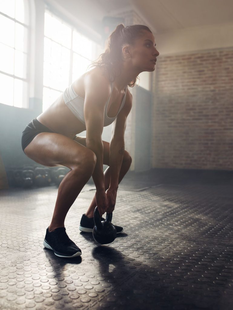 Fit woman exercising alone in a gym with a kettlebell