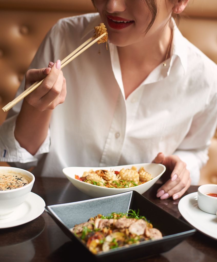 woman eating Asian food with chopsticks