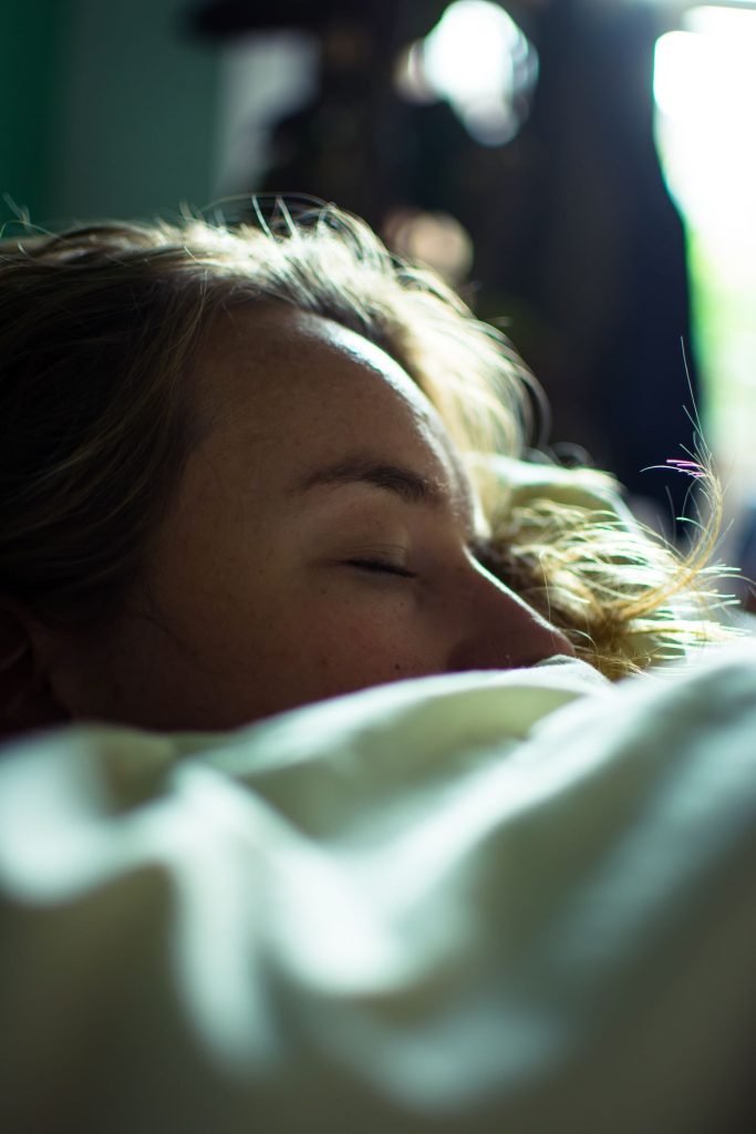 close up of woman sleeping in bed with covers up to her nose